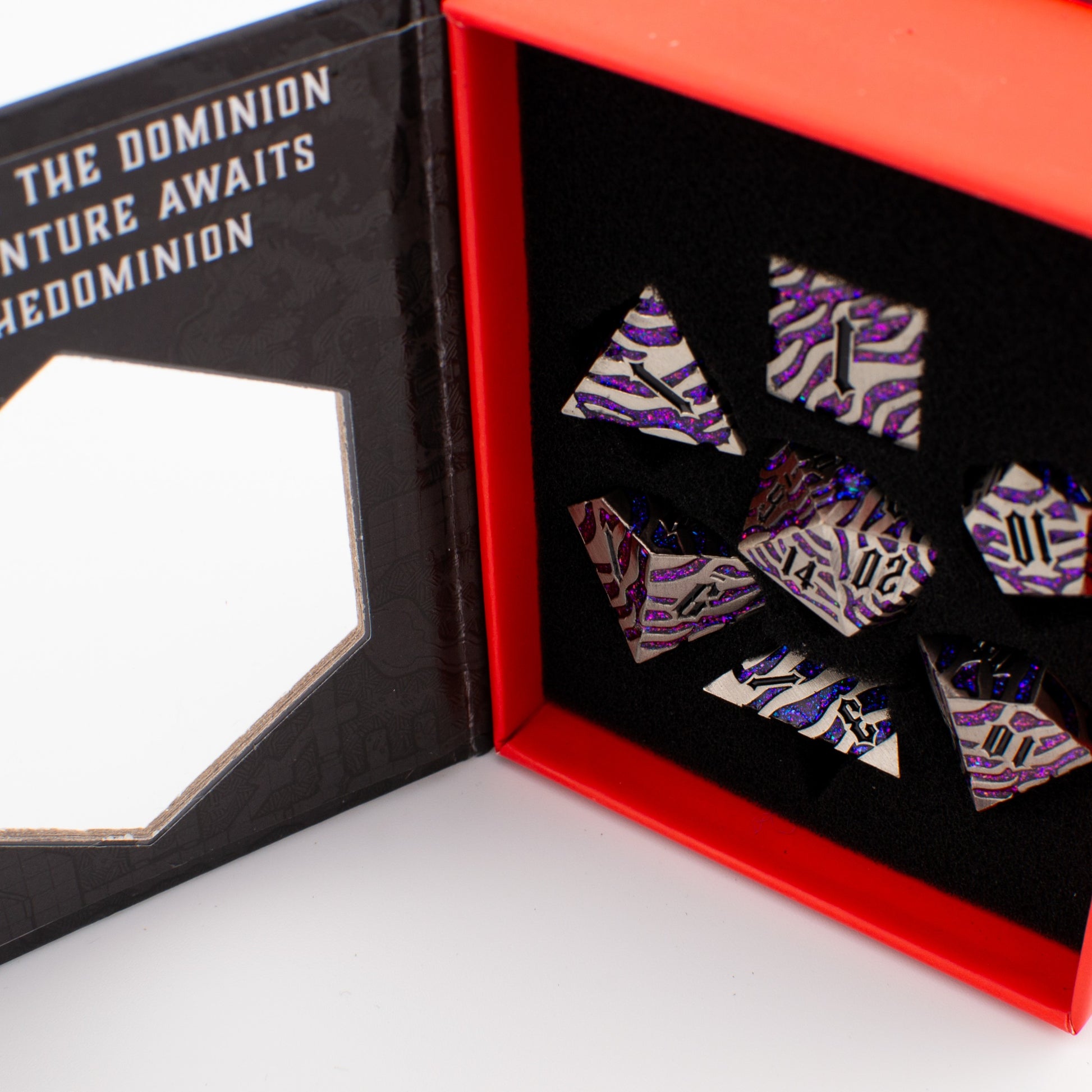 Close‑up of the Nebula Covenant solid metal D20 showing purple‑sparkle inlays, engraved detailing, and metallic silver finish.