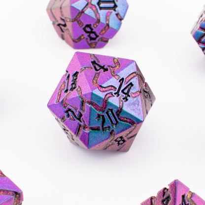 Close‑up view of the Void Weaver metal RPG dice showing purple and blue enamel inlays and detailed engraved patterns.