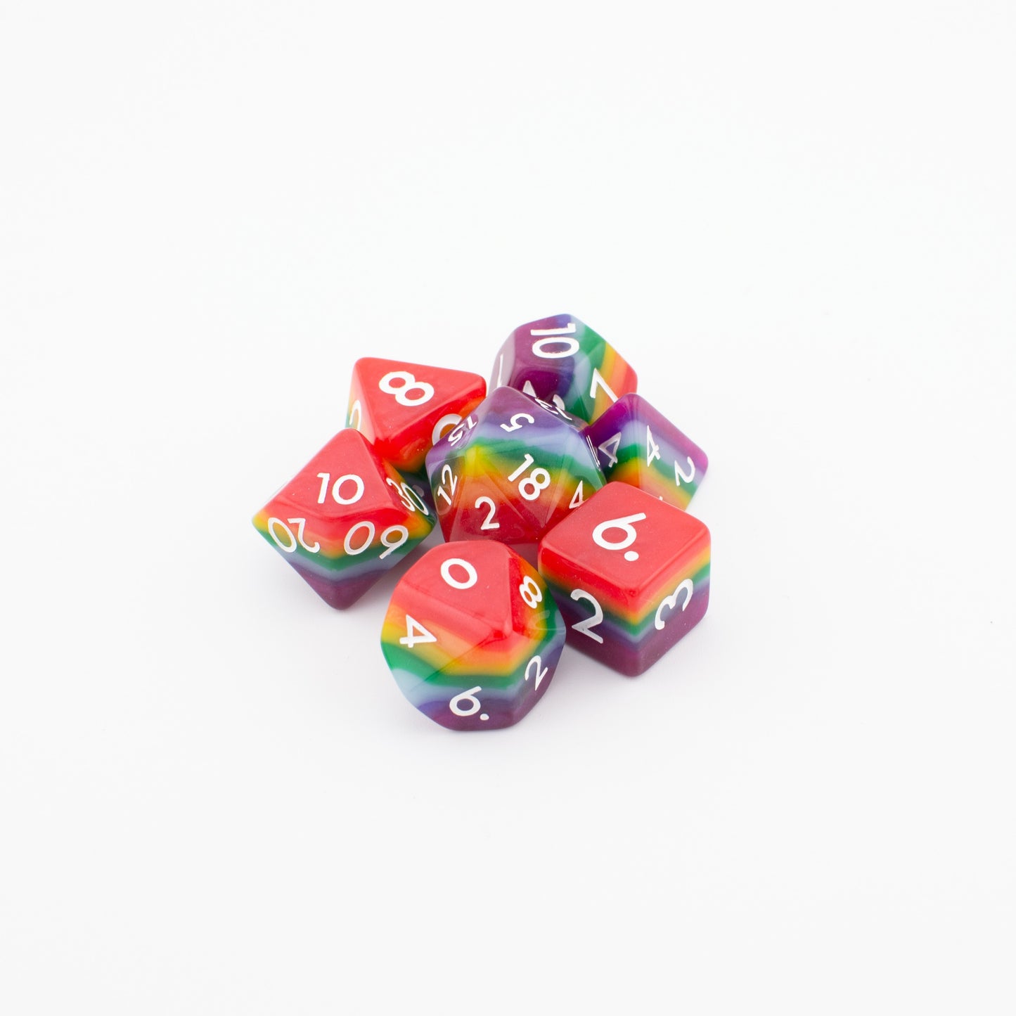 Rainbow Pride soft‑edge acrylic dice set arranged loosely on a white background, displaying all seven vibrant rainbow polyhedral dice.