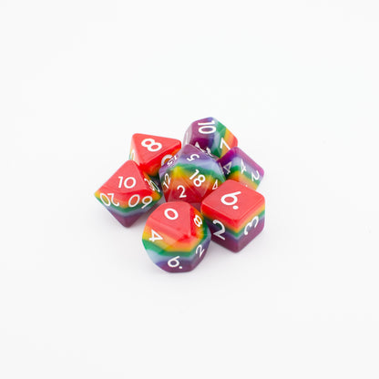 Rainbow Pride soft‑edge acrylic dice set arranged loosely on a white background, displaying all seven vibrant rainbow polyhedral dice.