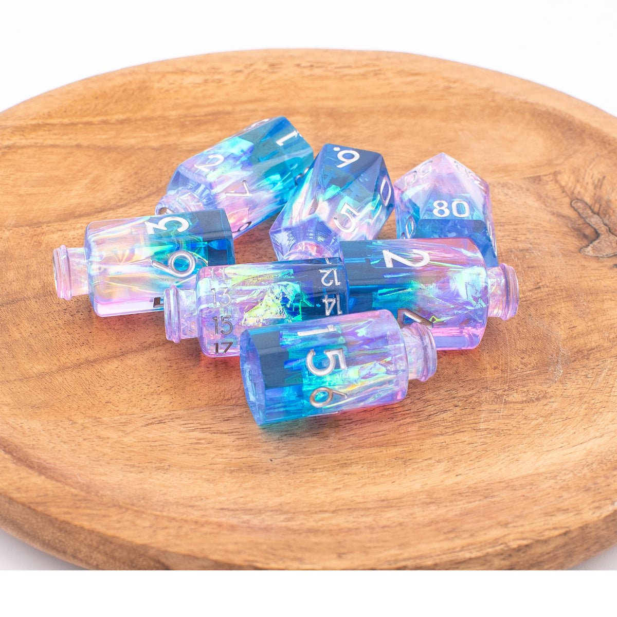 Tabletop Dominion Prismatic Elixir potion bottle dice shown loose on a wooden surface with iridescent blue‑purple resin and white numbering.