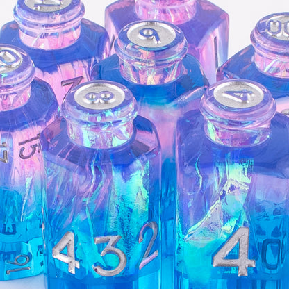closeup of Tabletop Dominion Prismatic Elixir potion bottle dice arranged together with iridescent pink‑blue resin and white numbering.