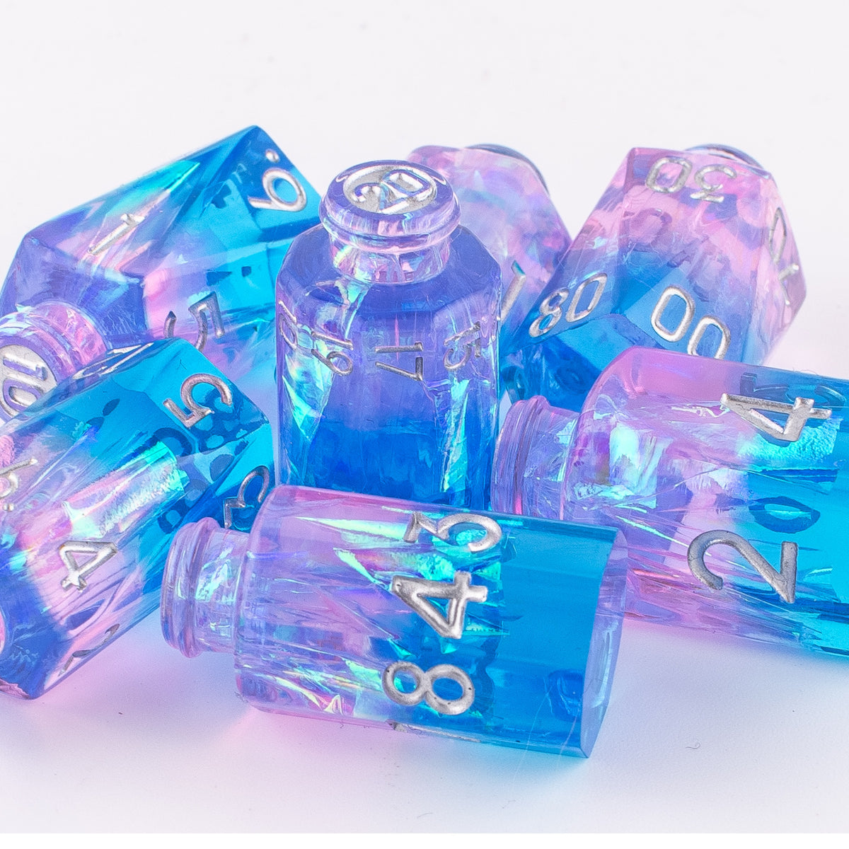 Tabletop Dominion Prismatic Elixir potion bottle dice piled together on a white background with blue‑pink iridescent resin and silver numbering.
