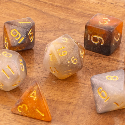 Clear Autumn acrylic dice arranged neatly on a wooden background, showing all seven soft‑edge dice with blended orange‑grey colouring.
