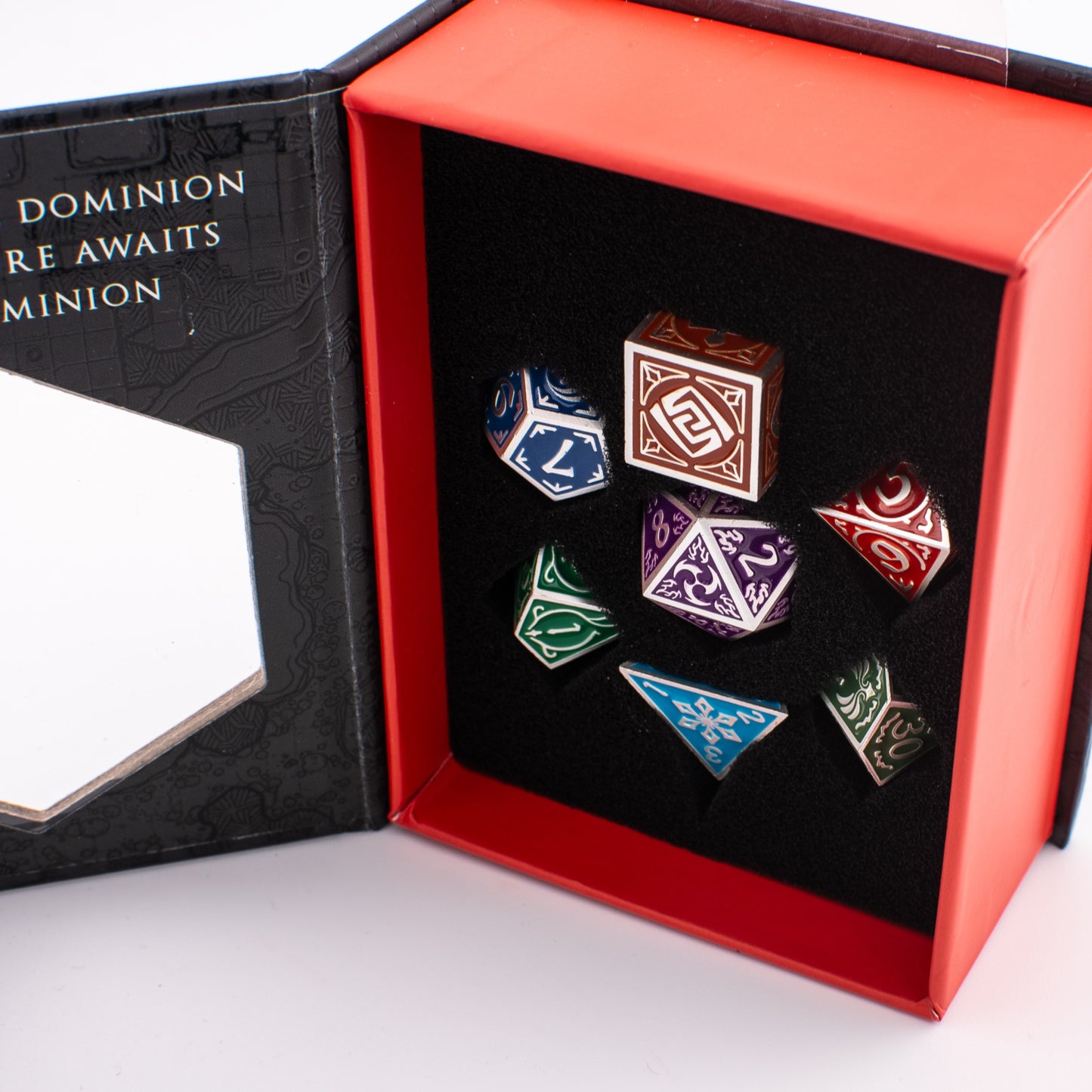 Tabletop Dominion Prismatic Elemental metal dice set displayed in an open box with multicoloured dice arranged in a foam insert.