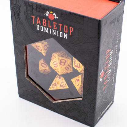 Tabletop Dominion Cheddar Champion heavy metal dice set in a closed display box with yellow dice and red numbering visible through the window.