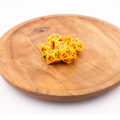 Tabletop Dominion Cheddar Champion heavy metal d20 dice arranged on a wooden plate, styled with a cheese‑like yellow texture and red numbering.