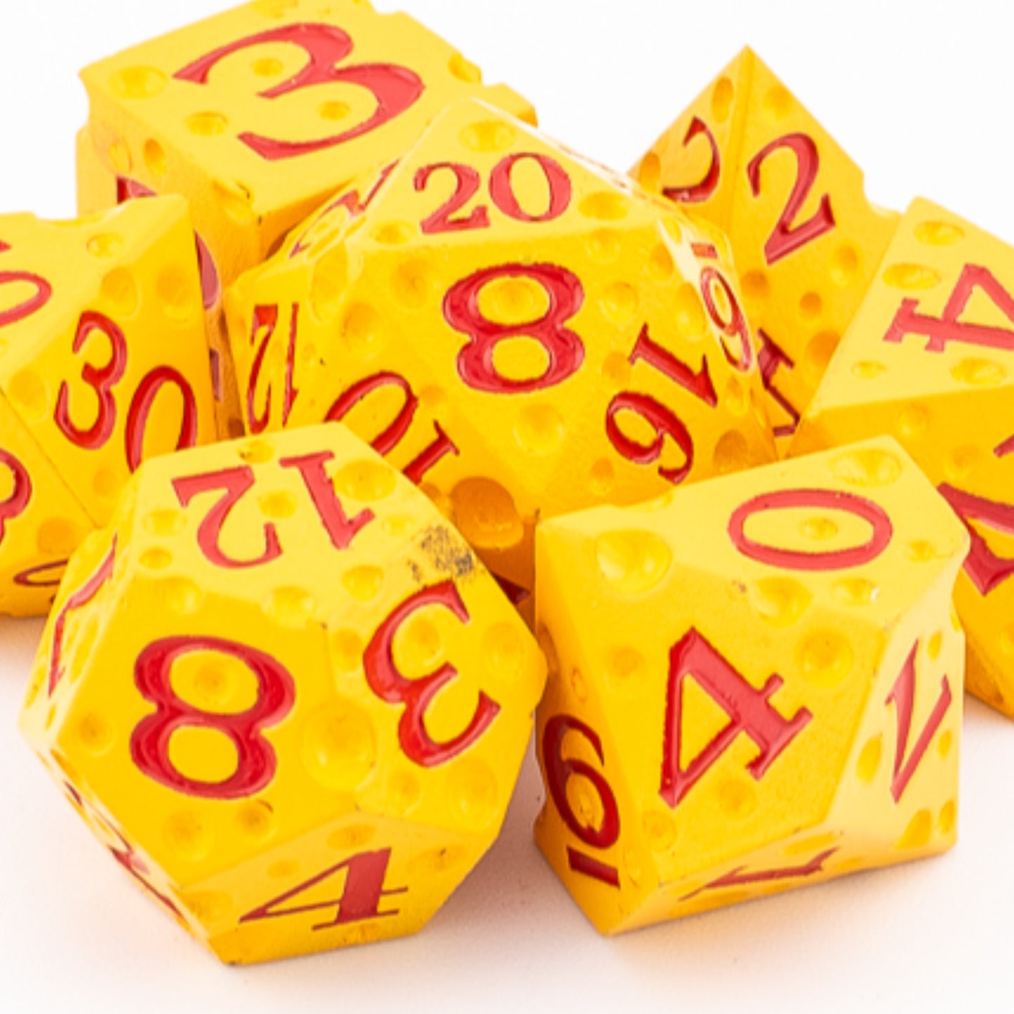 Tabletop Dominion Cheddar Champion heavy metal dice arranged together with a cheese‑like yellow texture and red numbering.
