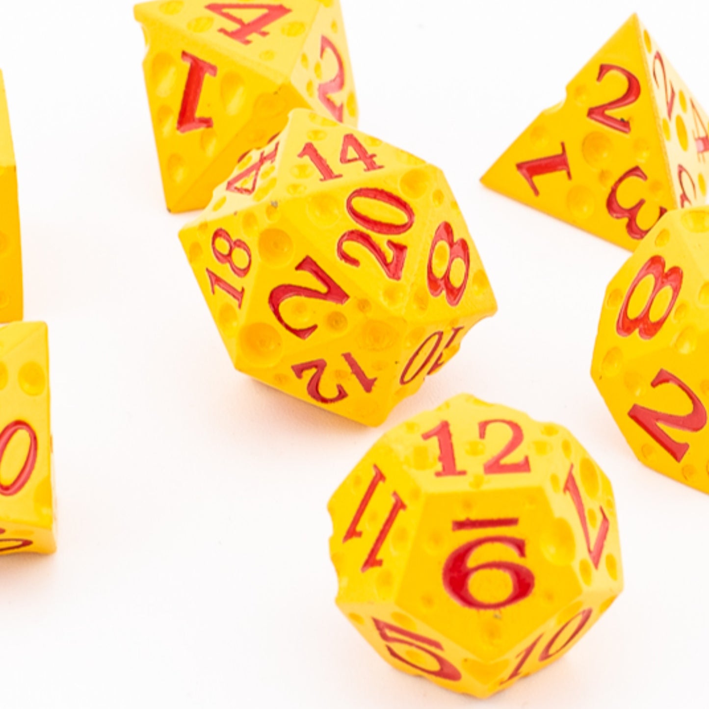 Tabletop Dominion Cheddar Champion heavy metal dice arranged together with a cheese‑like yellow texture and red numbering.