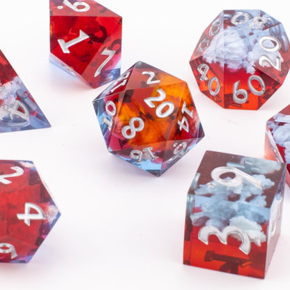 Ember Cloud resin dice clustered together on a white background, highlighting the swirling red and blue cloud inclusions inside each sharp‑edge die.